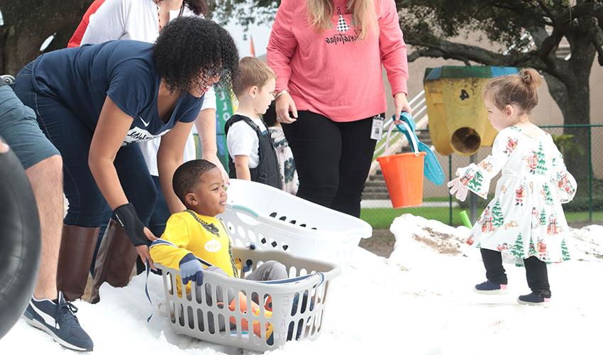 Mom pushing her son down the snow hill