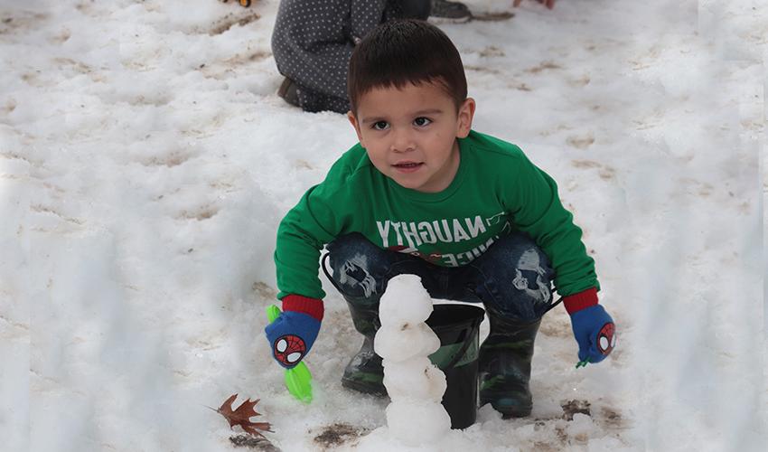 Little boy making a snow man