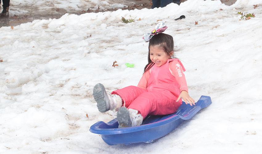 Little girl sliding down the snow hill