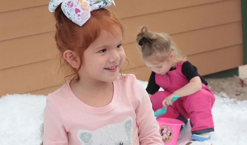 Girl smiling and another girl playing in the back